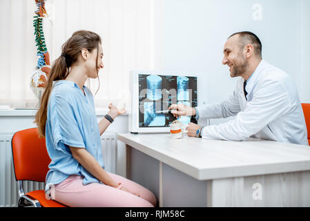 Junge Frau bei der medizinischen Beratung mit erfahrenen Therapeuten auf der Tomographie Drucken im Büro suchen Stockfoto