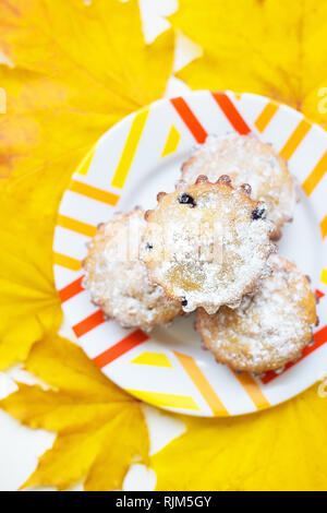 Farbige Cupcakes auf einer Platte und gelben Blätter im Herbst Stockfoto