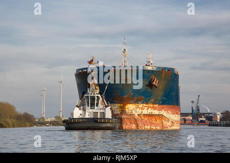 Containerschiff mit einem Schlepper im Hamburger Hafen Stockfoto