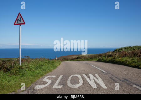 Eine Straße zum Meer mit einem Schild und die Warnung Wort langsam Stockfoto