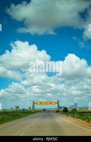 Blauer Himmel mit weißen Wolken Puffy führen zu der Fernen, Overhead gelb New Mexico State Line anmelden, auf 1-40 & Route 66, Texas verlassen Stockfoto