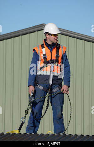 Ein Baumeister tragen eine Sicherheit zu nutzen, während der Arbeit in Höhen wartet auf Anweisungen von der Vorarbeiter Stockfoto