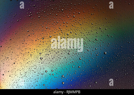 Tropfen Wasser auf das Glas im Licht des Regenbogens. Abstraktion. Hintergrund. Stockfoto