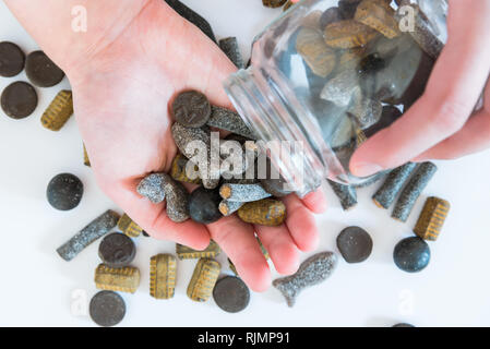 Gemischte Doppel gesalzene Lakritze von Candy jar in womans Hand gegossen werden Stockfoto