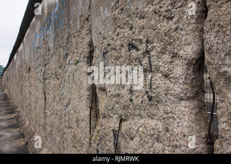 Berliner Mauer original verwitterten Abschnitt mit freiliegenden Bügeleisen bars und rauen Beton Textur in der Diagonale Perspektive Füllung der Rahmen beschädigt. Stockfoto