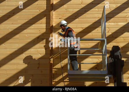 Handwerker Lackierung der Wand eines hölzernen Industriegebäude mit Holz Konservierungsmittel Stockfoto