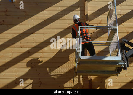 Handwerker Lackierung der Wand eines hölzernen Industriegebäude mit Holz Konservierungsmittel Stockfoto