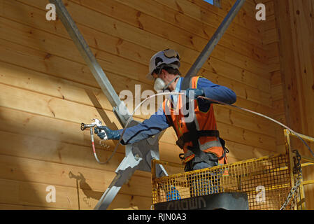 Handwerker Lackierung der Wand eines hölzernen Industriegebäude mit Holz Konservierungsmittel Stockfoto