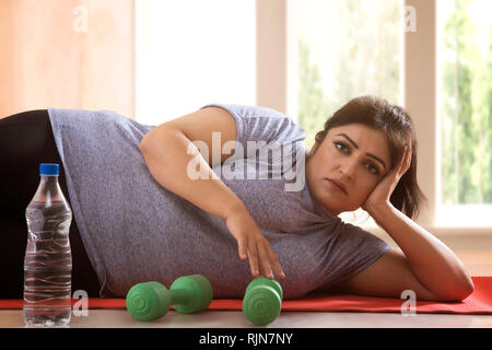 Faul traurig übergewichtige Frau auf dem Boden liegen und will sich nicht Übung Stockfoto