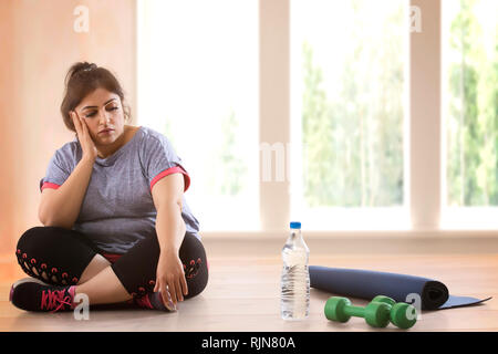 Deprimiert übergewichtige Frau sitzt auf dem Boden und nicht die Gewohnheit, Übung Stockfoto