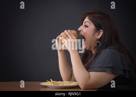 Dicke Frau, die einen Hamburger Essen Stockfoto