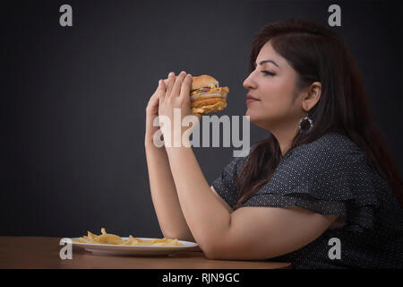 Dicke Frau, die einen Hamburger Essen Stockfoto