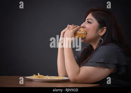 Dicke Frau, die einen Hamburger Essen Stockfoto