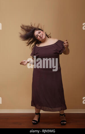 Fette Frau in einem langen braunen Kleid tanzen auf High Heels Stockfoto