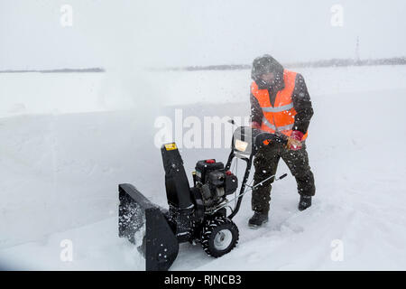 Arbeitnehmer beseitigt Schnee in einem Blizzard mit einem Schneepflug Stockfoto