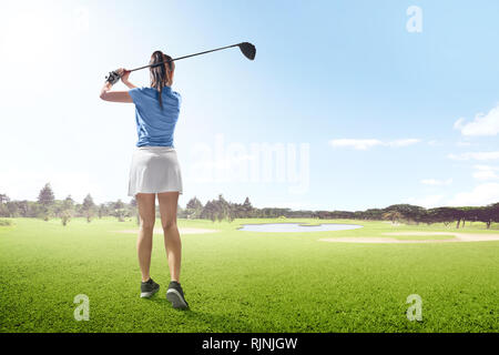 Ansicht der Rückseite des asiatischen Frau auf langen Fahrt Schwingen mit Holz Club Der Golfplatz mit Bunkern, Teich und Bäume am Morgen Stockfoto