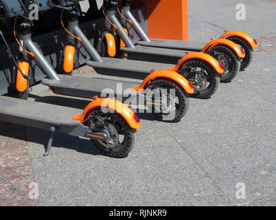 Elektroroller in Reihe auf dem Parkplatz. City bike rental System, öffentliche Tretroller auf der Straße Stockfoto