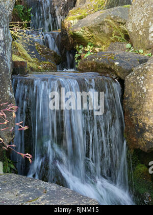 Wasserfälle in einem kleinen Bach im Garten machen das Wasser kommen zum Einsturz mit einer angenehmen, natürlichen Klang, über die Kanten im tiefen kleine Pools. Stockfoto