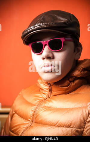 Junger Mann in Sonnenbrille mit rotem Rahmen in Leder Kappe Stockfoto