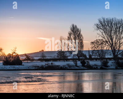 Eine schneereiche Winter Sonnenaufgang in Coate Water, Wiltshire in Richtung Liddington Hill suchen. Stockfoto