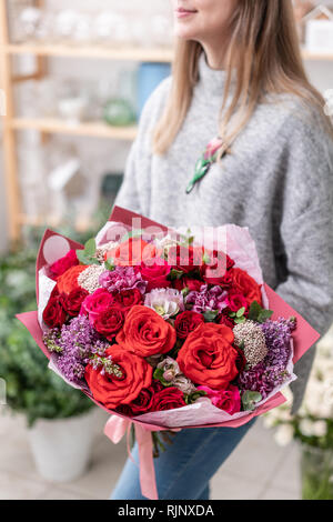 Schönen frischen Blumenstrauß aus gemischten Blumen in der Frau Hand. Die Arbeit der Florist in einem Blumenladen. Farbe rot Stockfoto