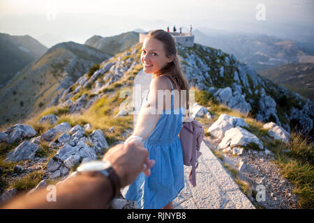 Inspiriert Mädchen Zeit damit verbringt, mit einem Kerl, der seine Hand im Hintergrund der Natur. Fröhliche junge Frau führt ein Freund der Berge. Lovcen Monten Stockfoto