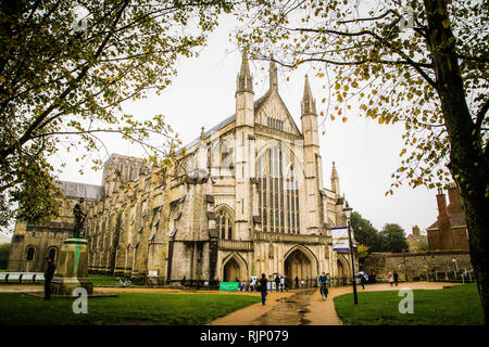 Winchester, Hampshire. Durch die Bäume an der Kathedrale von Winchester im Herbst, wie Leute über Ihren Tag. Stockfoto