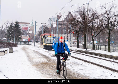 Ein Mann auf einem Fahrrad mit Straßenbahn nähert sich in Schnee, Plac Solidarnisci, Danzig, Polen Stockfoto