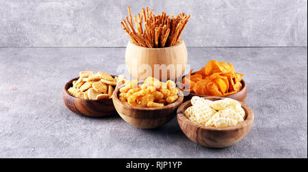 Salzige Snacks. Brezeln, Chips, Kekse in hölzernen Schüsseln. Ungesunde Produkte. Essen schlecht für Abbildung, Haut, Herz und Zähne. Sortiment von schnellen carbohydra Stockfoto