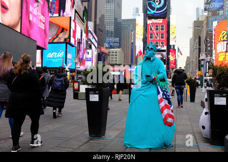 Ein Mann gekleidet, wie die Freiheitsstatue, die eine US-Flagge im Times Square warten auf Touristen Fotos mit ihm Tipps zu erwerben. New York City.NY USA Stockfoto