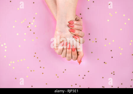 Die junge Frau mit der perfekten Coral Maniküre. Stockfoto
