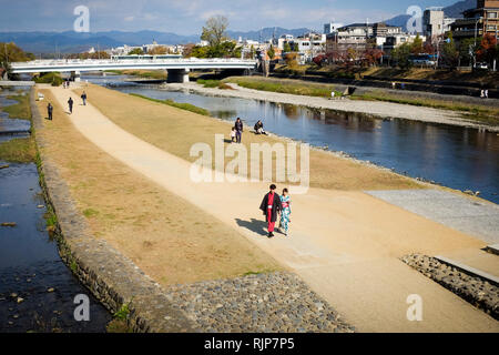 Menschen zu Fuß entlang der Stadt Kyoto Fluss Kamogawa, die wichtigste Wasserstraße, die durch die Stadt verläuft von Norden nach Süden. Stockfoto