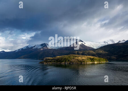 Eine sonnige Insel vor der Darwin Berge, gesehen von einem Kreuzfahrtschiff im Glacier Alley, Ushuaia, Argentinien, kurz nach Sonnenaufgang. Stockfoto