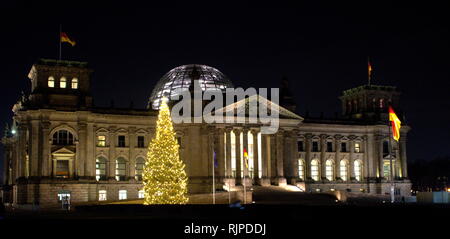 Ein Foto von der Außenseite des Reichstags, einem historischen Gebäude in Berlin, Deutschland, konstruiert, um den Reichstag des Deutschen Reiches. Ein großer Weihnachtsbaum leuchtet auf den Nachthimmel. Stockfoto