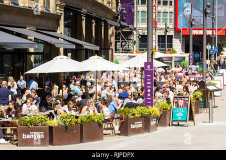 Ein Sommertag in Manchester Stadtzentrum mit vielen Menschen saßen Essen und Trinken außerhalb Banyan Bar und andere Restaurants und Bars des Dreiecks, für Stockfoto