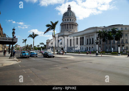 Zwei klassische restaurierten 1950er amerikanische Autos warten an der Ampel neben einem modernen Mercedes vor dem Capitolio Nacional in Havanna Stockfoto