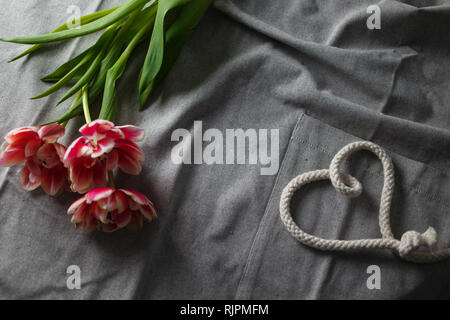 Herzen von Seil und Blumenstrauß aus Tulpen auf grauem Hintergrund mit Platz für Text Stockfoto