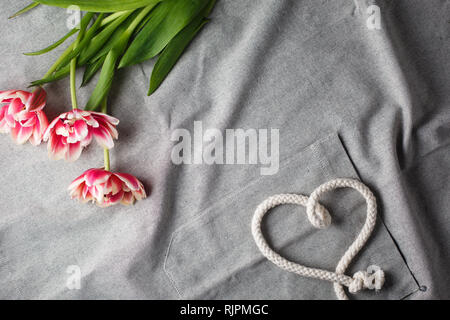 Herzen von Seil und Blumenstrauß aus Tulpen auf grauem Hintergrund mit Platz für Text Stockfoto