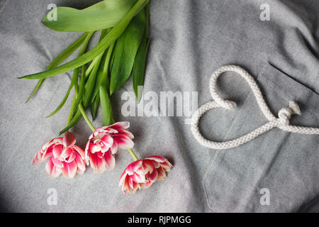 Herzen von Seil und Blumenstrauß aus Tulpen auf grauem Hintergrund mit Platz für Text Stockfoto