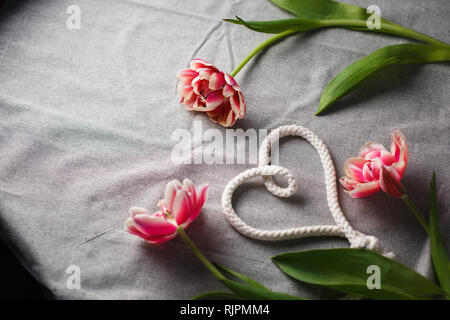 Herzen von Seil und Blumenstrauß aus Tulpen auf grauem Hintergrund mit Platz für Text Stockfoto