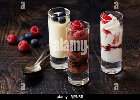 Stillleben mit drei Desserts in Gläsern mit Himbeeren und Blackberry garnieren Stockfoto