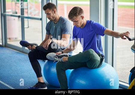 Läufer stretching auf Übung Kugeln in Indoor-laufbahn Stockfoto