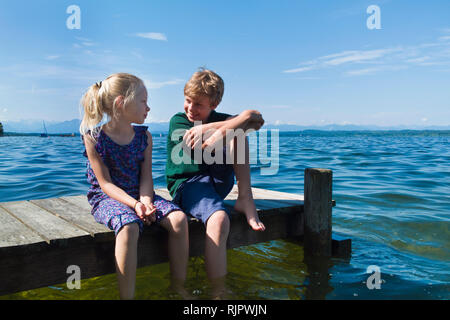 Geschwister Kühlung Füße im Wasser, Starnberger See, Bayern, Deutschland Stockfoto