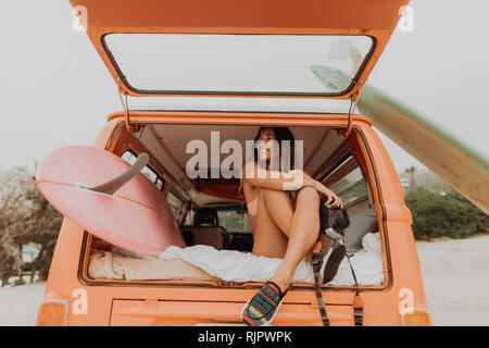 Junge Frau mit Instant Kamera an der Rückseite des recreational vehicle am Strand, Jalama, Kalifornien, USA Stockfoto