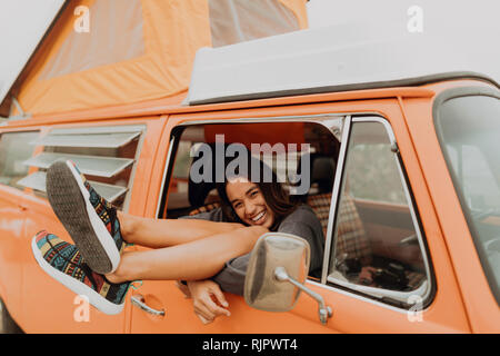 Junge Frau mit Beinen durch recreational vehicle Fenster am Strand, Porträt, Jalama, Kalifornien, USA Stockfoto
