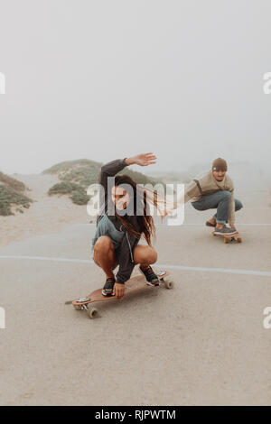 Junges Paar skateboarding in Misty Beach Parkplatz, Jalama, Kalifornien, USA Stockfoto