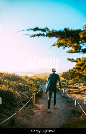 Surfer mit Surfbrett am Strand, Morro Bay, California, United States Stockfoto