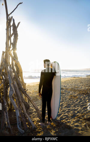 Surfer mit Surfbrett am Strand, Morro Bay, California, United States Stockfoto