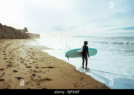 Surfer mit Surfbrett am Strand, Morro Bay, California, United States Stockfoto