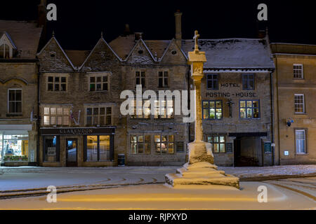 Der Marktplatz Kreuz vor der Kings Arms Pub vor Sonnenaufgang im Winter Schnee. Verstauen auf der Wold, Cotswolds, Gloucestershire, England Stockfoto